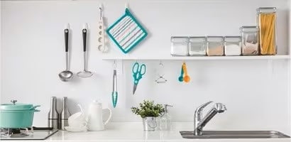 使用無痕掛勾在牆面上收納廚房用品
