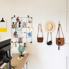 在牆面使用無痕掛勾掛起包包、帽子與收納網格，搭配小夾子掛起照片