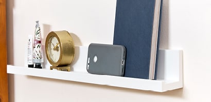 使用無痕層架在牆面收納鬧鐘、手機與書本
