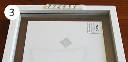 將無痕™ 相/畫框掛扣膠條貼在畫框背面上。
