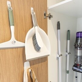 在牆面與櫥櫃內使用無痕掛勾與掃具收納夾來整理畚箕、掃把、拖把等清潔用具