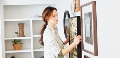 一名女子將相框掛置在牆面上
